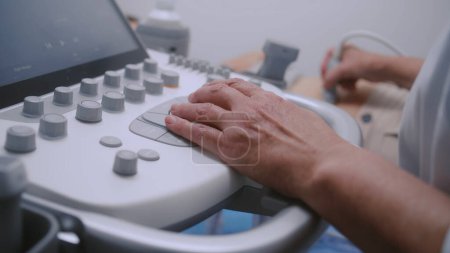 Photo for Close up of doctor using ultrasound machine with digital monitor. Professional medic performs abdominal organs sonography check up to female patient. Modern clinic or hospital with advanced equipment. - Royalty Free Image