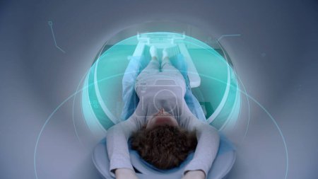 Téléchargez les photos : Femme subit une IRM ou un scanner, couchée sur le lit à l'intérieur de la machine. Effets visuels de la numérisation du cerveau et du corps des patientes. Équipement de haute technologie dans un laboratoire médical moderne avec des technologies de réalité augmentée. - en image libre de droit