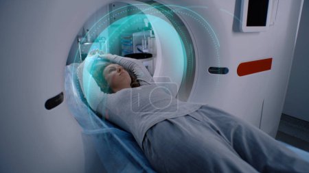 Photo for Woman undergoes MRI or CT scan procedure, lies on bed inside the machine. VFX animation of scanning brain and body of female patient. Advanced augmented reality equipment in modern medical lab with Ai - Royalty Free Image