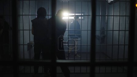 Foto de El alcaide trae a un nuevo prisionero a la cárcel y le quita las esposas. Adolescente afroamericano cumple condena de prisión en un centro penitenciario o centro de detención. Reclusos culpables en celdas de prisión. - Imagen libre de derechos