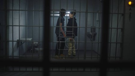 Foto de Prisioneros adolescentes multiétnicos luchan en celda de prisión. Un joven criminal empuja a su compañero de celda. Alcaide con bastón en la mano viene a calmar a los reclusos. Los adolescentes cumplen penas de prisión por delitos. Centro correccional. - Imagen libre de derechos