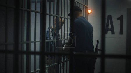 Photo for Warden takes off handcuffs from young prisoner. Teenager serves imprisonment term in correctional facility or detention center. Young inmate in prison cell. Justice system. View through metal bars. - Royalty Free Image