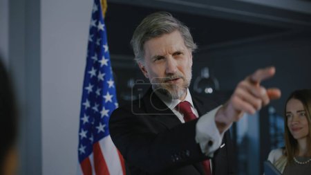 Photo for Positive United States Presidential Candidate gestures and poses for cameras after inspirational campaign speech or interview for media and television news. American politician at press conference. - Royalty Free Image