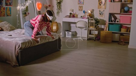Adolescente portant casque AR joue réalité virtuelle jeux vidéo en ligne dans sa chambre confortable. Fille passer du temps libre et s'amuser à la maison. Concept de dispositifs modernes, divertissement et style de vie.
