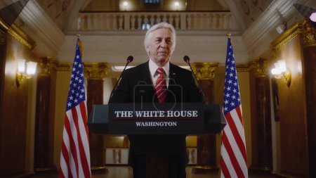 Photo for Serious President of the United States gives inspirational political speech in the White House. Senior US government representative speaks at press conference for media. American flags in background. - Royalty Free Image