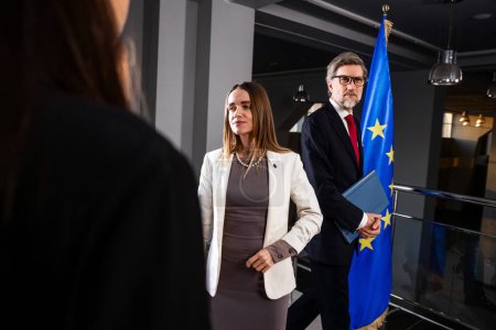Photo for Positive female Representative of the European Union poses for the cameras and greets journalists. Correspondents take photos and broadcast on TV. EU politician at the beginning of press conference. - Royalty Free Image
