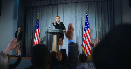 Presidential of USA candidate delivers campaign speech, answers questions, gives interview. American republican politician performs at meeting with press. Election day. Backdrop with American flags.