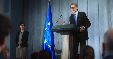 Photo for Female representative of media asks question to European politician performing at press conference. Confident EU consul makes an announcement, delivers campaign speech, gives interview. Election day. - Royalty Free Image