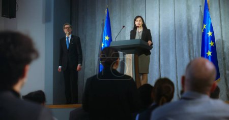 Female politician comes to tribune, delivers campaign speech, answers journalists questions, gives interview to media. Representative of the European Union performs at press conference. Elections day.