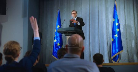 Photo for Confident politician makes an announcement, delivers campaign speech, gives interview to journalists and media. Mature representative of the European Union performs at press conference. Election day. - Royalty Free Image