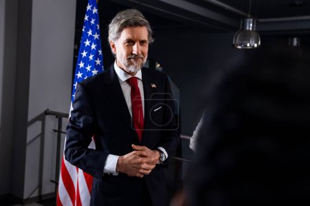 Photo for President of the USA during press conference. Positive American politician waves his hand and poses for cameras after inspirational speech or interview with journalists for media and television news. - Royalty Free Image