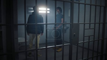 Multi ethnic teen prisoners fight in prison cell. Young criminal pushes cellmate. Warden with baton in hand comes to calm inmates. Teenagers serve imprisonment terms for crimes. Correctional facility.