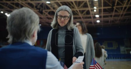 Photo for Female American citizen comes to vote in polling station. Political races of US presidential candidates. National Election Day. - Royalty Free Image