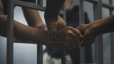 Photo for Warden takes off handcuffs from young prisoner. Multi ethnic teenagers serve imprisonment term in correctional facility or detention center. Young inmates in prison cell. Justice system. Close up. - Royalty Free Image