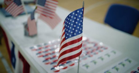 Close up of American flag standing on the table at polling place. Elections in the United States of America. Presidential race and election coverage. Concept of civic duty, democracy and patriotism.