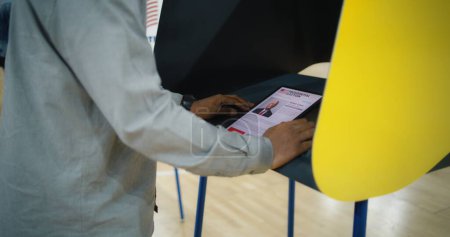 US-Bürger nutzen Tablet-Computer zur Stimmabgabe. Afroamerikaner, männliche Wähler wählen und wählen in der Wahlkabine im Wahllokal. Präsidentschaftswahlen in den Vereinigten Staaten von Amerika. Bürgerpflicht.