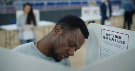 African American male voter comes to voting booth. American citizens come to vote in polling station. Political races of US presidential candidates. National Election Day in United States. Close up.