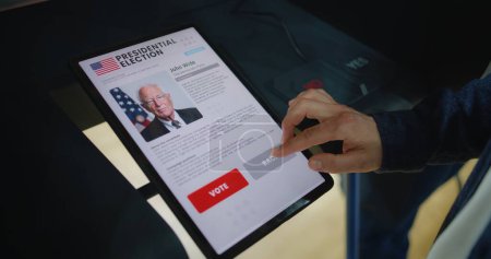 Nahaufnahme eines kaukasischen Mannes, der in der Wahlkabine mit einem Tablet-Computer die Wahl trifft und für den US-Präsidentschaftskandidaten stimmt. US-Bürger am Nationalwahltag in den Vereinigten Staaten im Wahllokal.