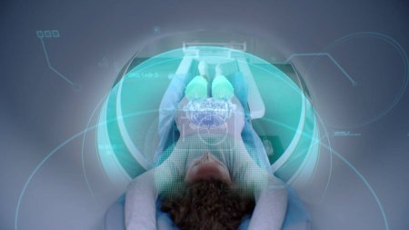 Foto de La mujer se somete a una resonancia magnética o una tomografía computarizada, yace en la cama dentro de la máquina. Efectos visuales del escaneo del cerebro y el cuerpo del paciente femenino. Equipo de alta tecnología en laboratorio médico moderno con tecnologías de realidad aumentada. - Imagen libre de derechos