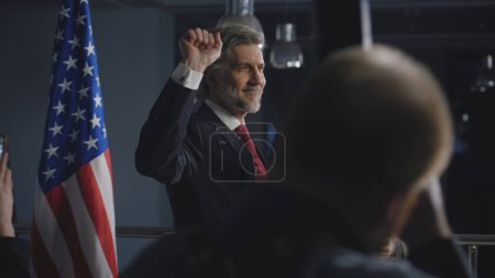 Photo for Positive American politician comes to journalists and poses for cameras after political speech. President of the United States of America before interview for media and TV news during press campaign. - Royalty Free Image
