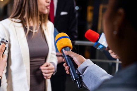 Photo for Political speech of EU consul during press campaign. Confident female European politician answers journalists questions, gives interview for media and television news in European Parliament building. - Royalty Free Image