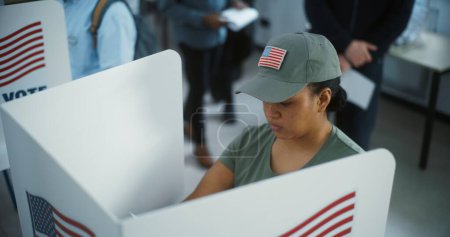Téléchargez les photos : Une femme soldat de l'armée américaine vote dans un bureau de vote moderne. Journée nationale des élections aux États-Unis. Courses politiques des candidats à la présidence américaine. Devoir civique et concept de patriotisme. - en image libre de droit