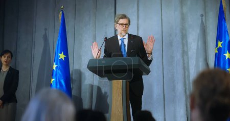 Photo for Mature representative of the European Union performs at press conference. Confident politician makes an announcement, delivers campaign speech, gives interview to journalists and media. Election day. - Royalty Free Image