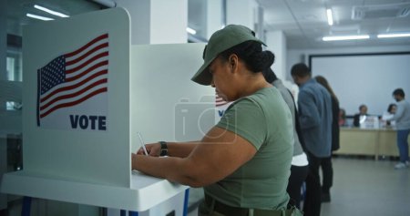 Téléchargez les photos : Une femme soldat de l'armée américaine vote dans un bureau de vote. Journée nationale des élections aux États-Unis. Courses politiques des candidats à la présidence américaine. Concept de devoir civique. Dolly shot. - en image libre de droit