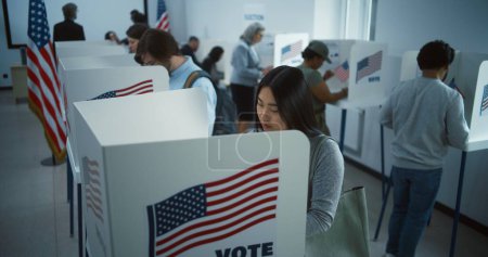 Téléchargez les photos : Une Asiatique vient voter dans un bureau de vote. Journée nationale des élections aux États-Unis. Courses politiques des candidats à la présidence américaine. Concept de devoir civique. Au ralenti. Dolly shot. - en image libre de droit
