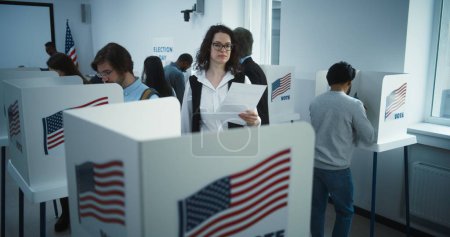 Téléchargez les photos : Une femme à lunettes vient voter dans un bureau de vote. Journée nationale des élections aux États-Unis. Courses politiques des candidats à la présidence américaine. Concept du devoir civique. Au ralenti. Dolly shot. - en image libre de droit