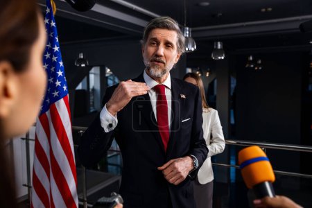 Photo for Serious United States Presidential Candidate answers journalists questions, gives interview for media and TV news in government building. American politician during press conference. Political speech. - Royalty Free Image