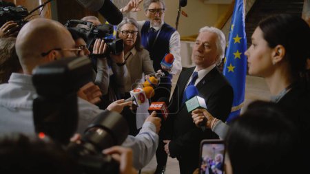 Photo for EU representative answers press questions and gives interview for TV breaking news. Senior consul surrounded by crowd of journalists. Political speech during press conference. State of the nation. - Royalty Free Image