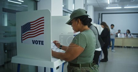Soldatinnen der amerikanischen Armee wählen in der Wahlkabine im Büro eines Wahllokals. Nationaler Wahltag in den Vereinigten Staaten. Politische Rennen der US-Präsidentschaftskandidaten. Konzept der Bürgerpflicht. Dolly erschossen.