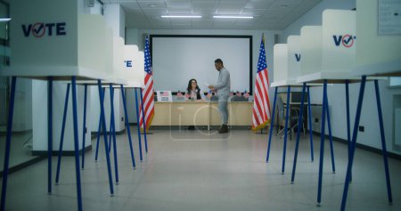 Téléchargez les photos : Un citoyen américain, un homme afro-américain qui se rend au bureau de vote pour s'inscrire, prend un bulletin papier pour voter. Jour national des élections aux États-Unis d'Amérique. - en image libre de droit