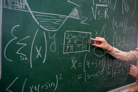 Téléchargez les photos : Belle enseignante près du tableau noir apprendre les mathématiques en classe, vue arrière - en image libre de droit
