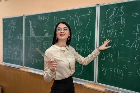 Téléchargez les photos : Jeune femme écrivant des équations mathématiques sur le tableau noir en classe, apprendre - en image libre de droit