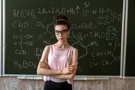 Téléchargez les photos : Enseignante explane formules chimiques près tableau, concept éducatif - en image libre de droit