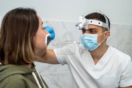 Foto de El médico masculino examina la nariz de un paciente con rinitis. Comprobación de nariz. Examen médico de la nariz. Concepto de salud y medicina. - Imagen libre de derechos