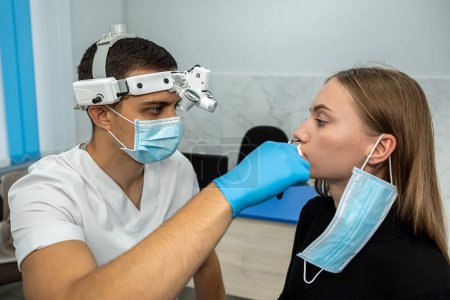 Foto de Retrato de un otorrinolaringólogo mientras trabajaba con una paciente con problemas nasales. medicina. examen de los senos nasales - Imagen libre de derechos