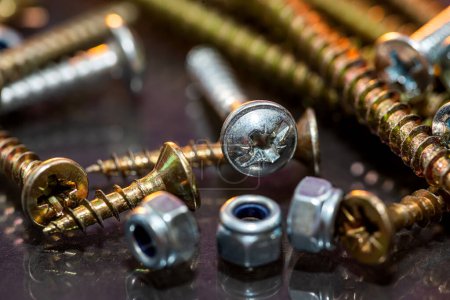 Photo for Close-up image of sets of plastic dowels and shiny metal self-tapping screws in a pile on a table background. Screws close up. - Royalty Free Image