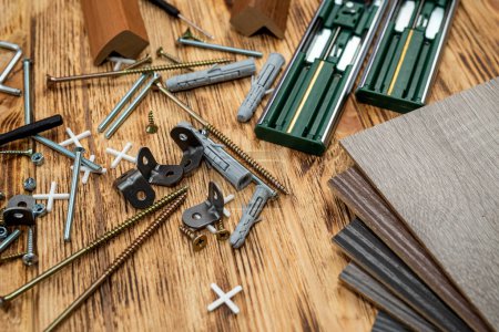 Photo for Wooden samples of furniture accessories next to dowels, screws and a key on a wooden table. the concept of furniture assembly. repair - Royalty Free Image