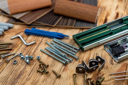 Photo for Dowels and screws with keys are scattered next to samples of wooden examples for home furniture. The concept of furniture assembly - Royalty Free Image