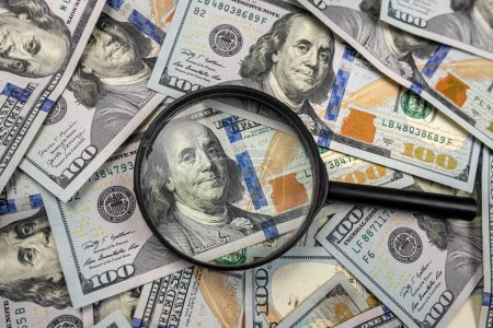 Foto de Lupa de aumento descansa en dólares americanos y magnifica sobre un fondo blanco. lupa y dólares. ver de cerca el dinero - Imagen libre de derechos