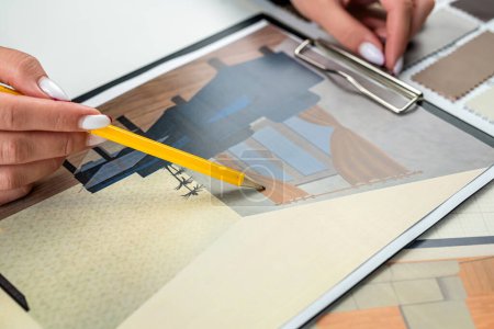 Téléchargez les photos : Designer femme planifie l'intérieur de la maison illustre et choisit des couleurs parfaites pour la nouvelle maison avec des échantillons de matériaux en bois sur la table. Idées d'affaires pour la conception immobilière. - en image libre de droit