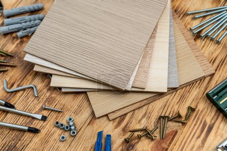 Photo for Wooden samples of furniture accessories next to dowels, screws and a key on a wooden table. the concept of furniture assembly. repair - Royalty Free Image