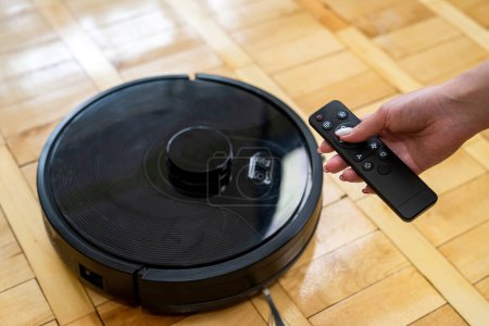 robot vacuum cleaner on a laminated wooden floor with a remote control. smart cleaning technology. robot