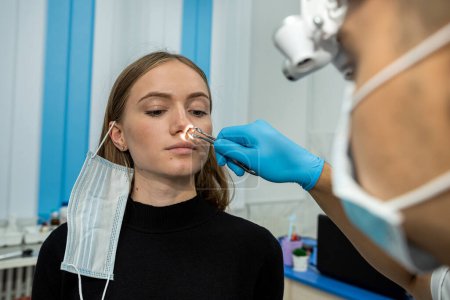 Foto de Retrato de un otorrinolaringólogo mientras trabajaba con una paciente en un examen de los senos paranasales. medicamento para la congestión nasal - Imagen libre de derechos
