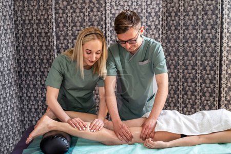Photo for Two massage therapists a woman and a man give a four-handed anti-cellulite leg massage to a female client in a spa salon. massage in four hands. spa treatments - Royalty Free Image