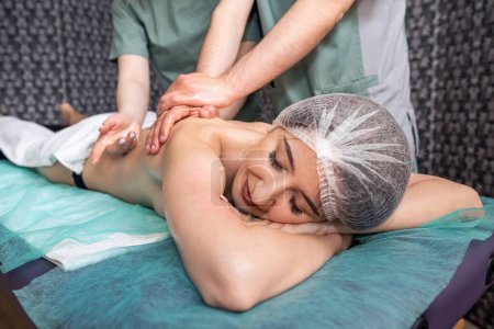 Photo for Back massage in four hands at the same time - two professional massage therapists deal with a female patient. spa salon. skin healing. muscle tone - Royalty Free Image
