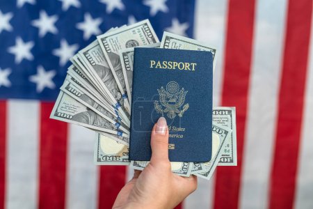 Foto de Female hands holding american passport with dollar cash over american flag closeup. travel concept. - Imagen libre de derechos